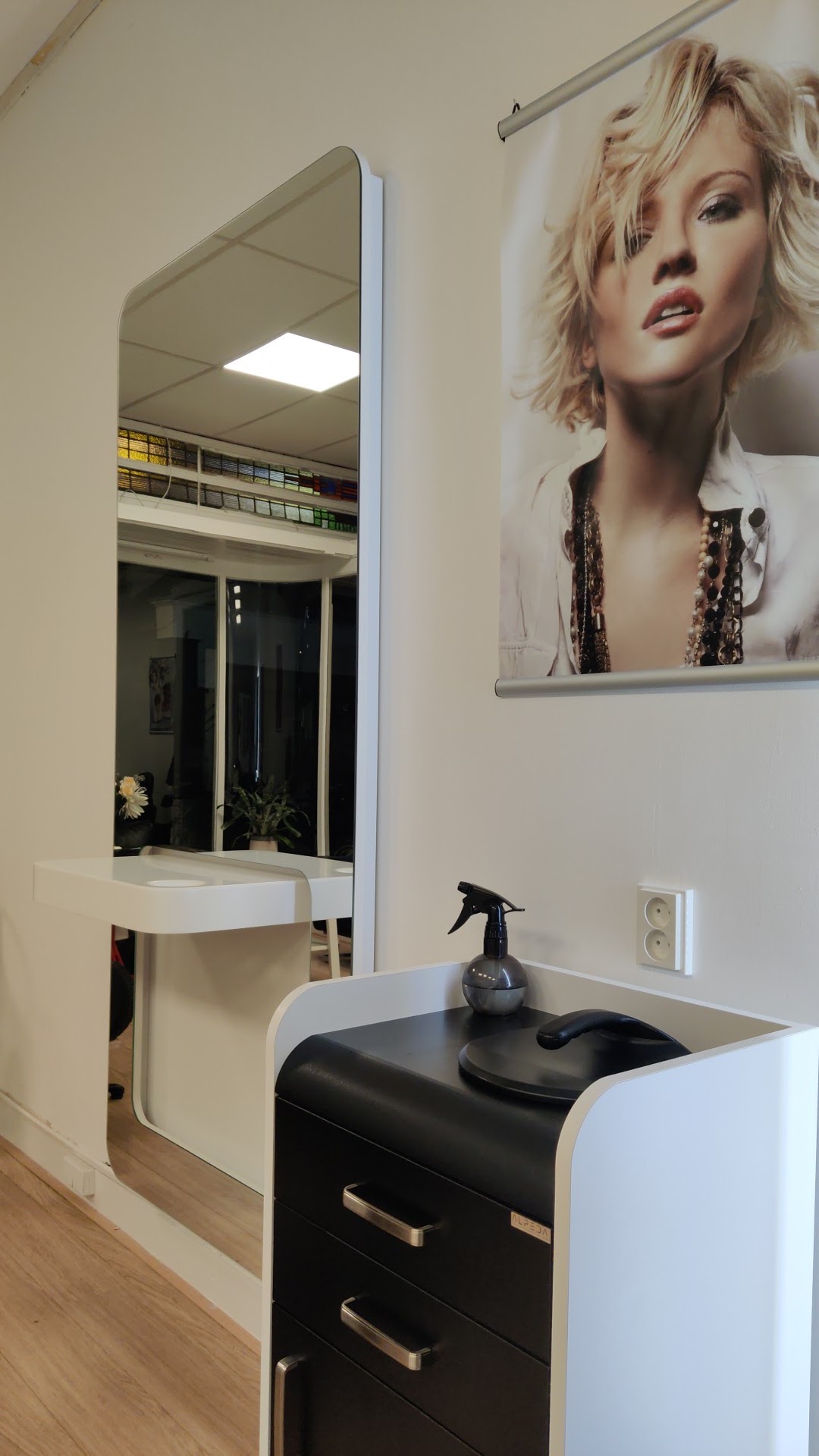 Hoek van de salon met verlichte spiegel, kaptafel en poster